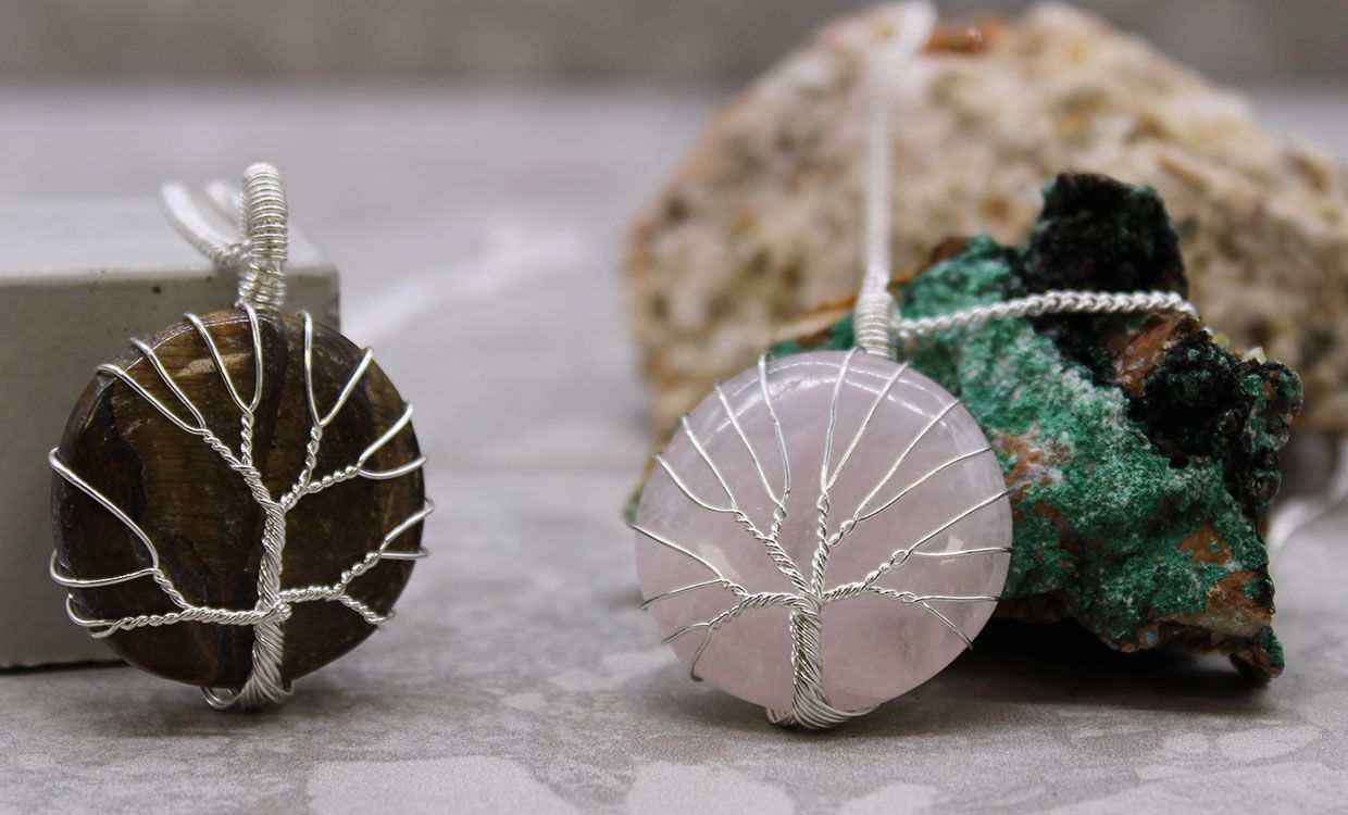 Two tree-shaped pendants on strings with a natural stone background